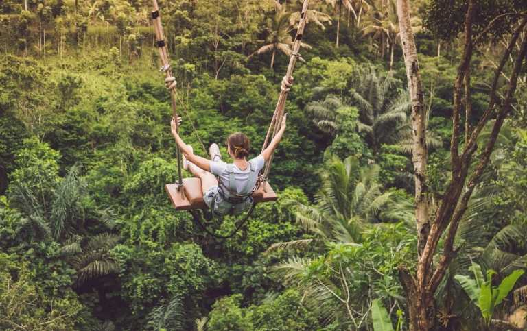Woman on a swing in a tropical forest in Indonesia.