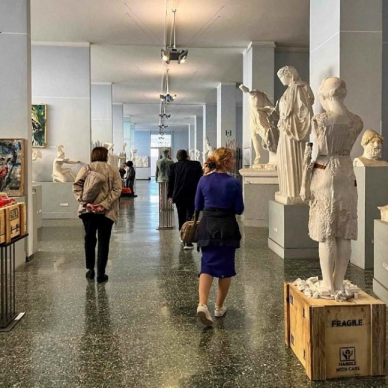 Alexandra Balogh promenerar i en museisal med kopior av antika skulpturer.
