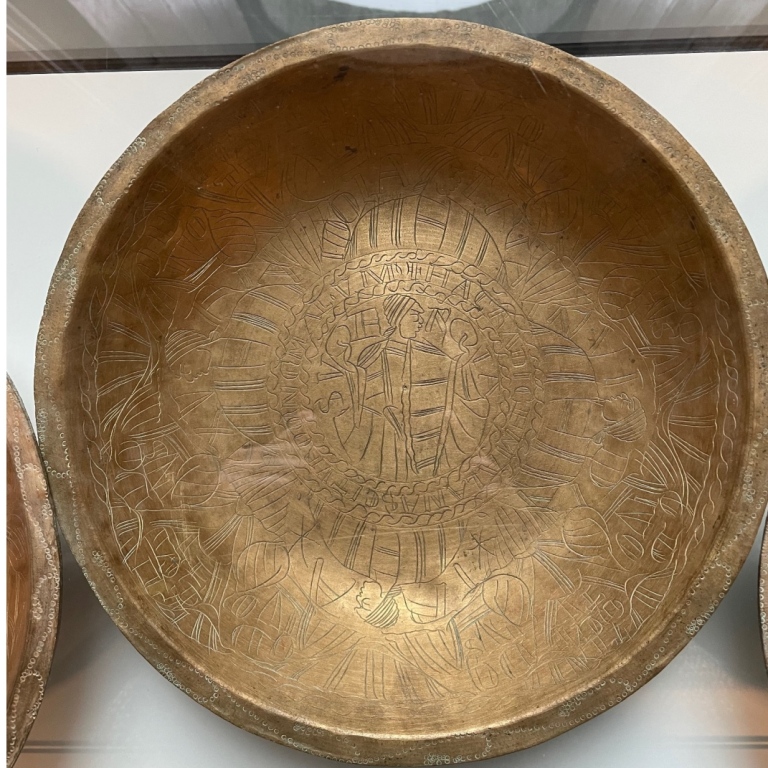 A wide bowl made of brass with engravings