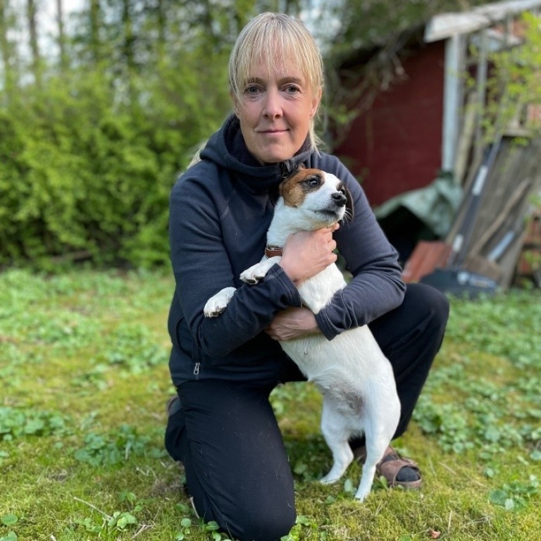 Hanna Johannesson på knä med en liten hund i famnen.