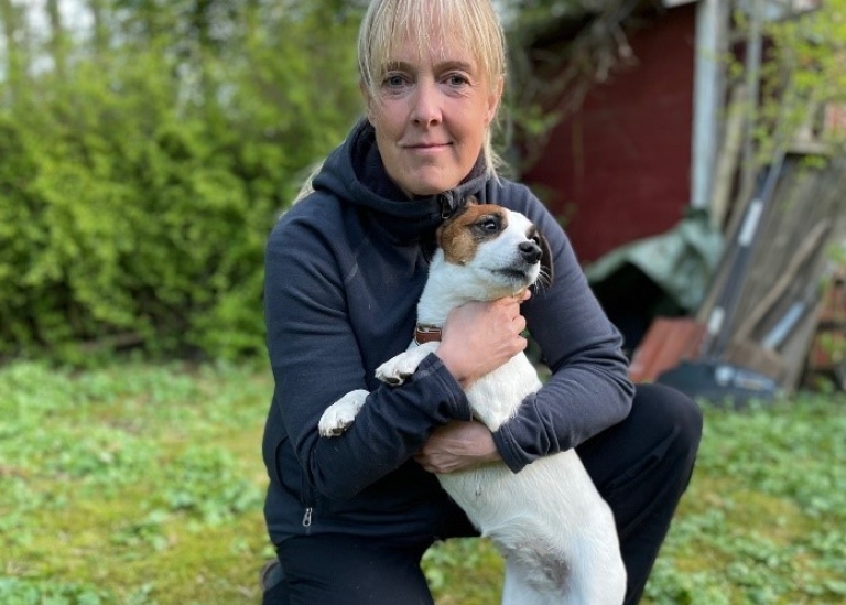 Hanna Johannesson på knä med en liten hund i famnen.