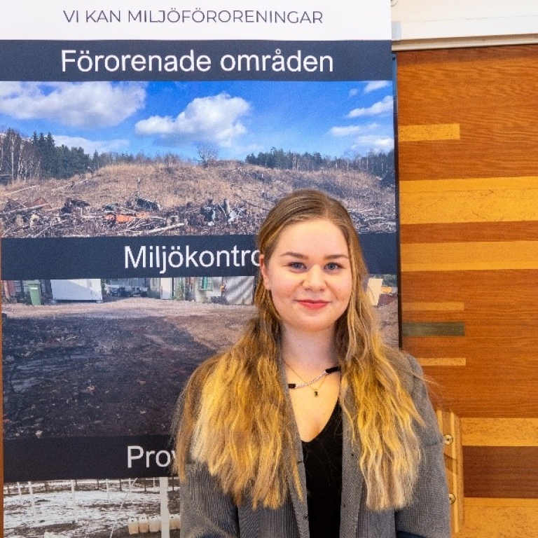 Anna Qviström in front of sign about environmental pollution.