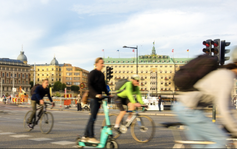 Personer på cyklar och elsparkcyklar i Stockholms stadsmiljö.