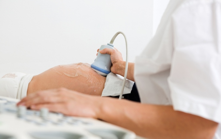 Läkare undersöker gravid mage med ultraljudsskanning