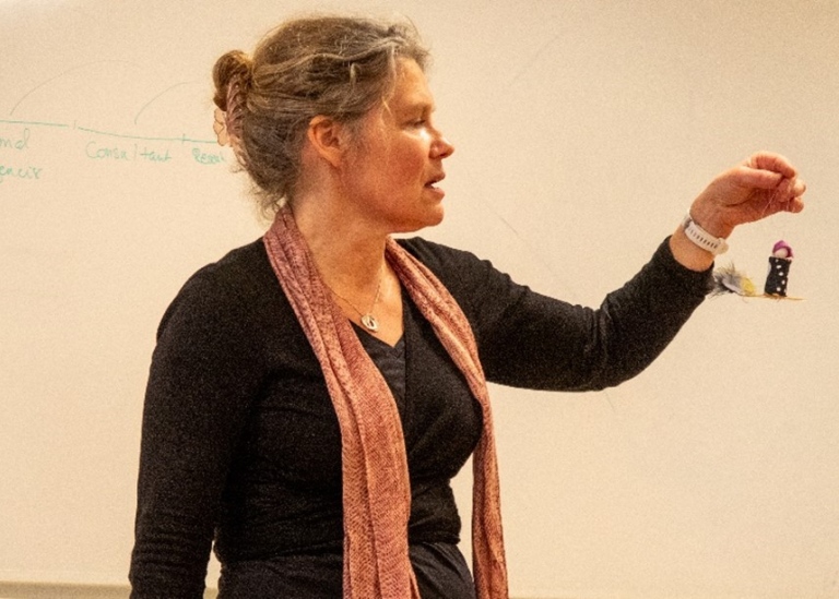 Petra Wallberg lectures students and shows a small Easter witchflying backwards.