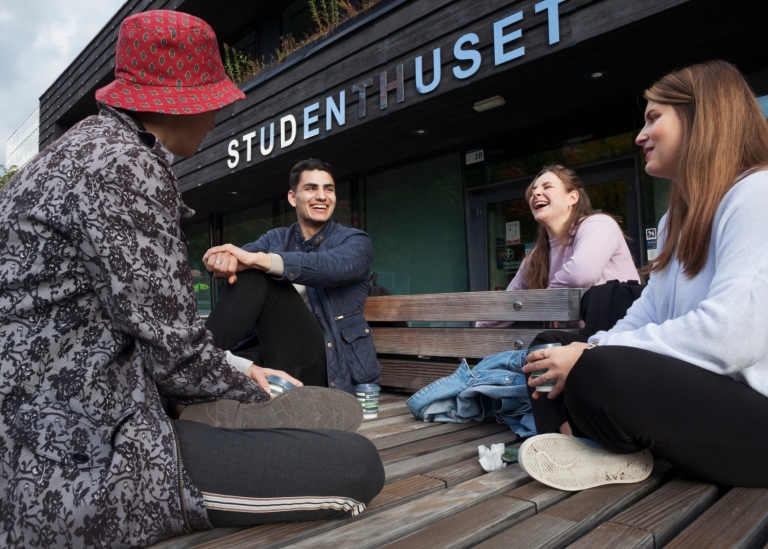 Fyra studenter dricker kaffe och skrattar utanför studenthuset på Frescati.
