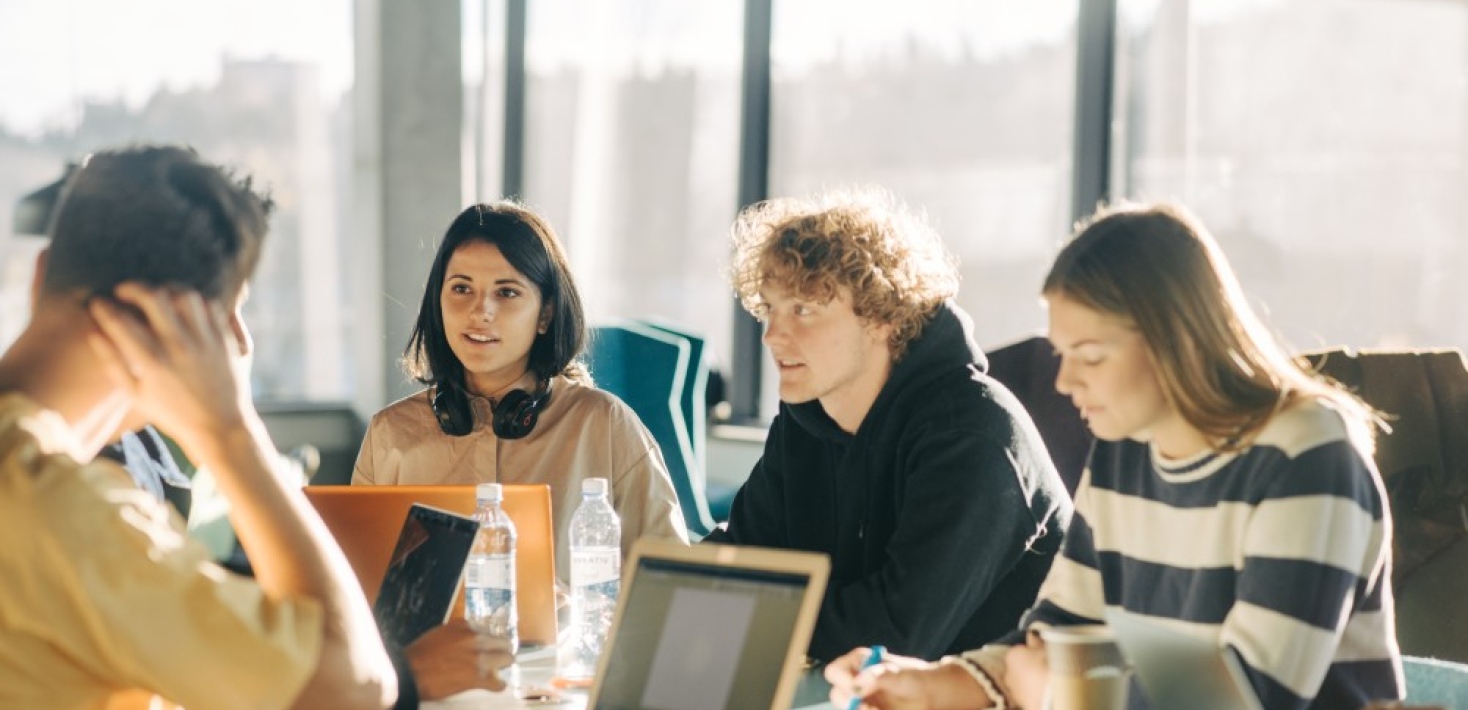 Students sitting at table talking. 