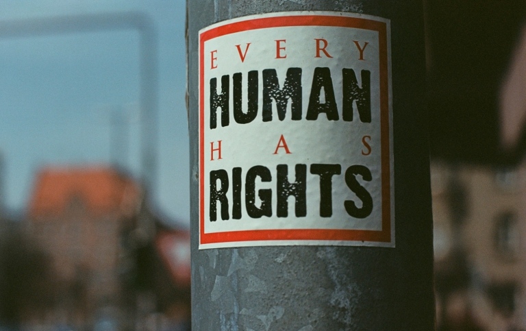 Genrebild: en lyktstolpe med klistermärke på, texten lyder: "Every human has rights"