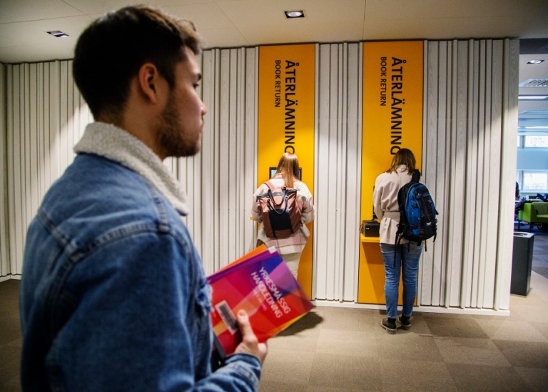 Låntagare lämnar tillbaka böcker i bibliotekets återlämningsautomat