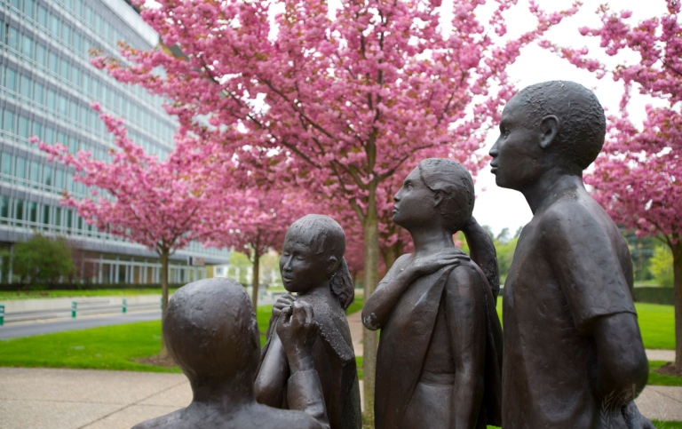 Staty till minne av 30-årsdagen av utrotningen av smittkoppor. Den finns vid Världshälsoorganisationens (WHO:s) huvudkontor i Geneve. © WHO / Christopher Black Staty i gjuten brons och sten som föreställer fyra personer, där en är en flicka som vaccineras