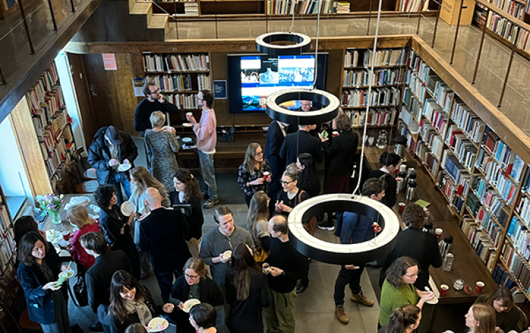 Firandet i institutionens bibliotek. Människor minglar i ett bibliotek.